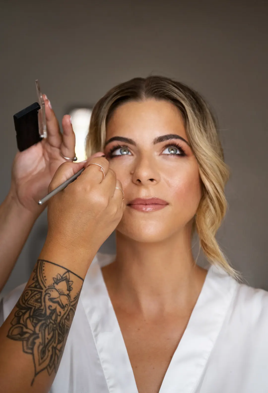 Una donna sorridente durante il trucco prima di un servizio fotografico