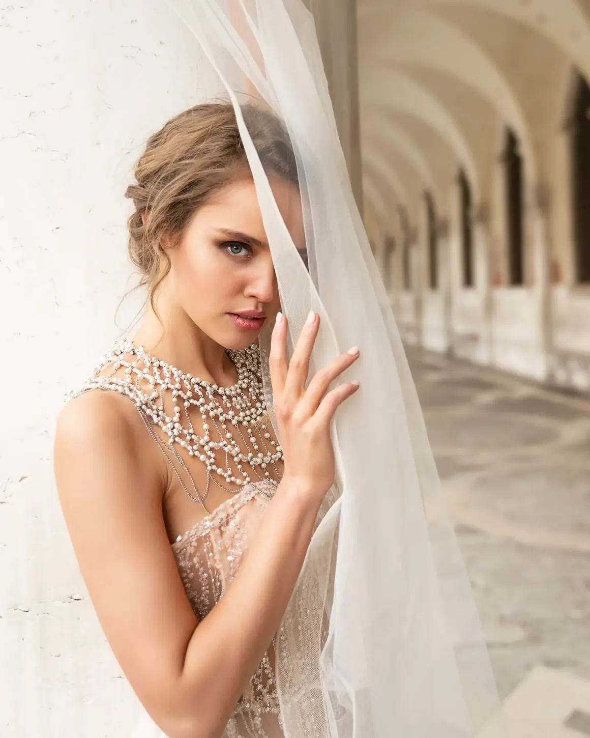 Una donna in abito da sposa con il velo, sotto un porticato