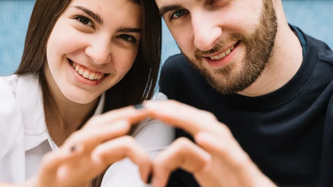Ein lächelndes Paar formt mit den Händen ein Herz